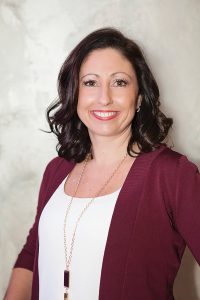 Headshot of Angela Judson wearing white shirt under maroon blazer against light background