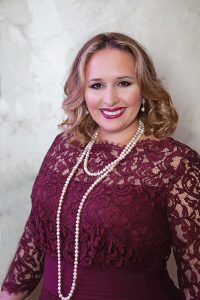 Headshot of Christi Kidd wearing maroon-laced dress against light background
