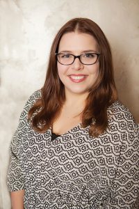Headshot of Courtney Watson wearing black and white patterned blouse against light background