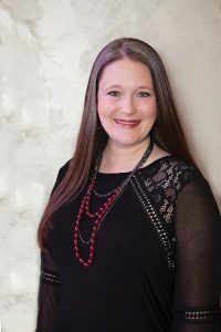 Headshot of Elizabeth Marley wearing black blouse with maroon necklace against light background
