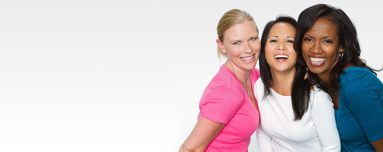 Three diverse women wearing pink, white and blue shirts aligned right on off-white background