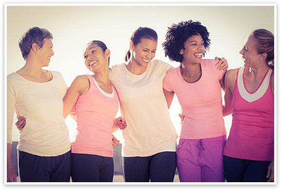 Five diverse women wearing workout clothes holding each other in a row and smiling