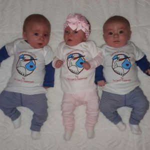 Three newborn triplets wearing same "Delivered with Love" shirts